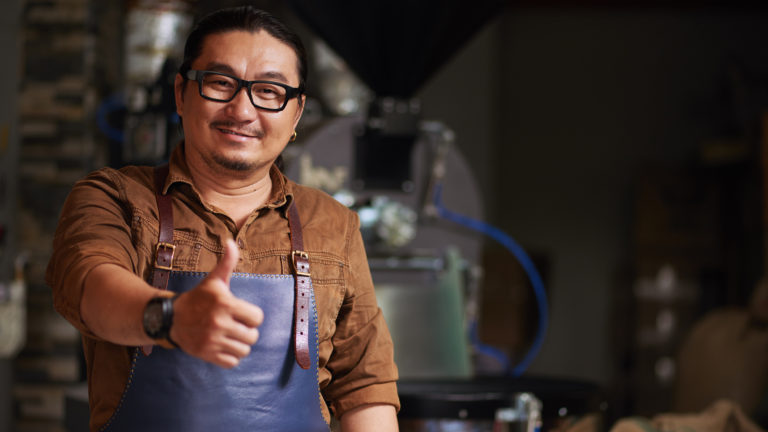 Cheerful roastery owner in glasses showing thumbs-up